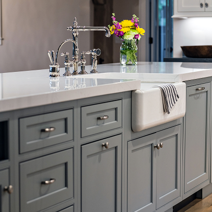 Gray kitchen cabinets with farmhouse sink and vintage-style bridge faucet