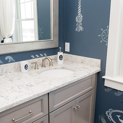 Coastal bathroom vanity with nautical blue walls, marble countertop, and rope design accents