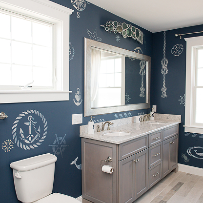Nautical themed bathroom with navy walls, gray vanity, and coastal wall decor