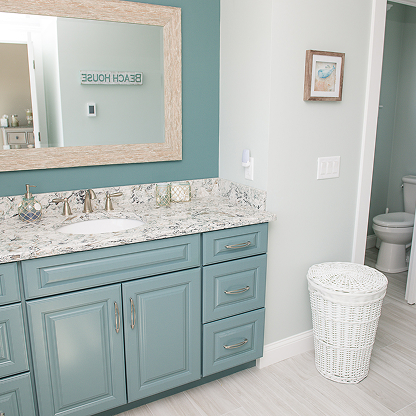 Beach house bathroom with seafoam blue vanity, marble countertop, and coastal decor