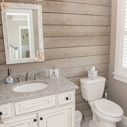 Farmhouse bathroom with shiplap accent wall, white vanity, and distressed mirror frame