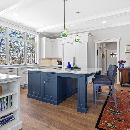 Coastal kitchen featuring navy blue island, white cabinets, and glass globe pendant lighting