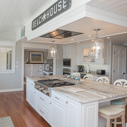 Beach house kitchen with white cabinets, marble countertops, and 'Beach House' sign detail