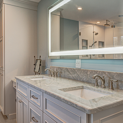 Modern bathroom with light blue vanity, marble countertop, and custom mirror lighting