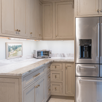 Contemporary kitchen design with light gray cabinets, marble countertops and stainless steel appliances
