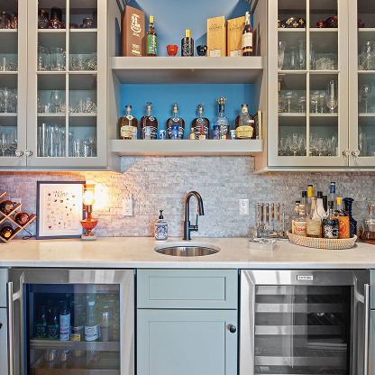 Custom home bar with glass-front cabinets, blue backsplash, premium liquor display and wine refrigerator