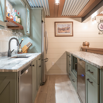Sage green basement bar with shiplap walls, marble countertops and custom liquor storage