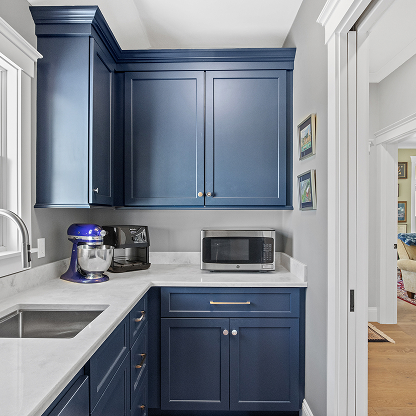 Modern kitchen with navy blue shaker cabinets, white countertops and small appliances
