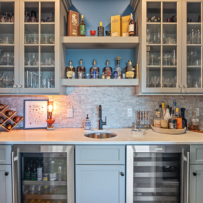 Custom home bar with glass-front cabinets, marble countertops and dual beverage fridges
