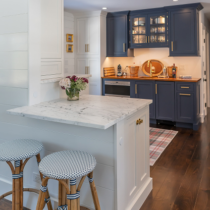 Modern kitchen with navy cabinets, marble peninsula and houndstooth bar stools