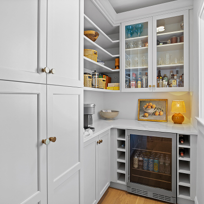 Custom white pantry with glass-front cabinets, beverage center and brass hardware
