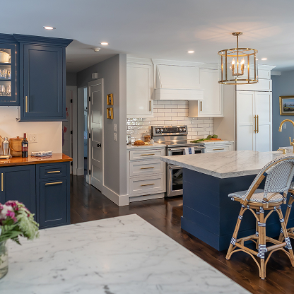 Navy and white kitchen with marble countertops, brass fixtures and bistro bar stools