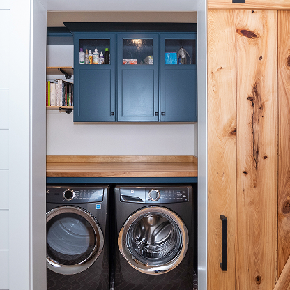 Modern laundry closet with navy cabinets, butcher block counter and barn door