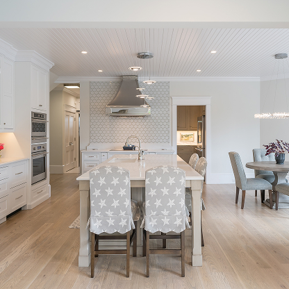 Coastal kitchen with star-patterned bar stools, white cabinets and geometric backsplash