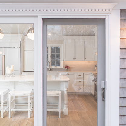 White coastal kitchen with sliding glass door and hardwood floors