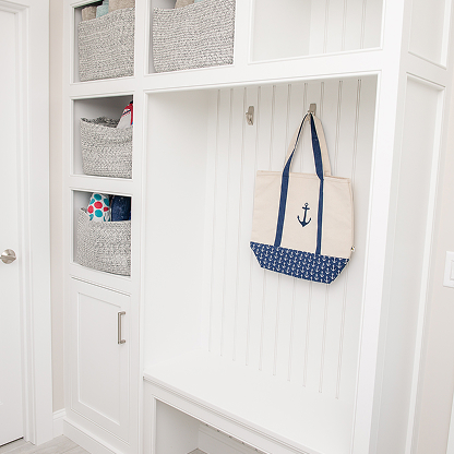 White mudroom with built-in storage, shiplap walls and nautical accents
