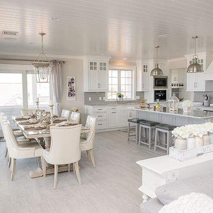 Open concept white kitchen and dining room with crystal chandelier and gray accents