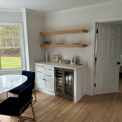 Built-in wine bar with floating wood shelves, white cabinets, and beverage center