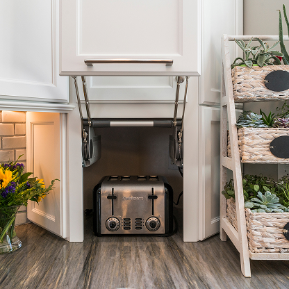 Kitchen storage solution featuring appliance garage with lift-up door mechanism, retro toaster, and decorative plant ladder shelf display