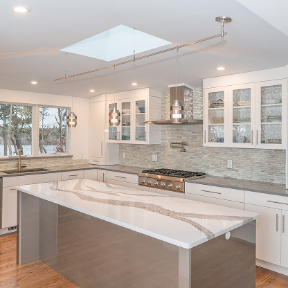 Bright modern kitchen with skylight, marble waterfall island and glass cabinets - luxury white kitchen renovation