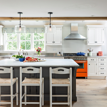 White kitchen with orange range, gray island and glass pendant lights - modern farmhouse design