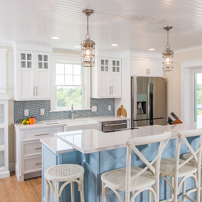 Coastal kitchen with blue island, white shaker cabinets, geometric backsplash and lantern pendants - modern farmhouse style