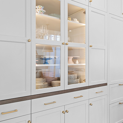 Custom white glass cabinet storage with LED lighting and brass hardware - luxury kitchen organization