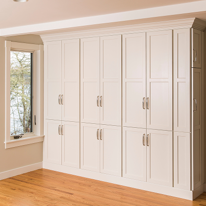 Floor-to-ceiling white storage cabinets with brass handles - custom mudroom organization system