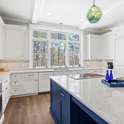 White kitchen with navy blue island, large windows and glass pendant - coastal modern design