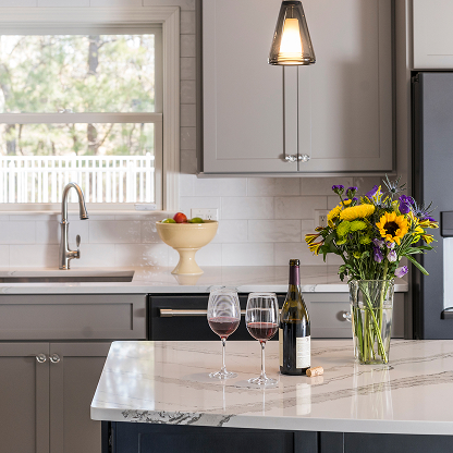 Gray kitchen with marble counters, wine display and fresh sunflower arrangement - modern farmhouse style