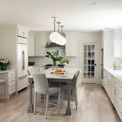 Modern white kitchen with gray island, globe pendants and upholstered barstools - transitional design