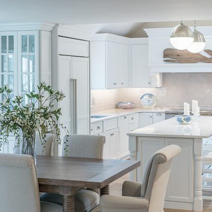 Transitional white kitchen with upholstered dining chairs and custom glass cabinets - coastal elegant design
