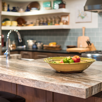 Contemporary kitchen countertop with decorative bowl of fresh produce and blue tile backsplash