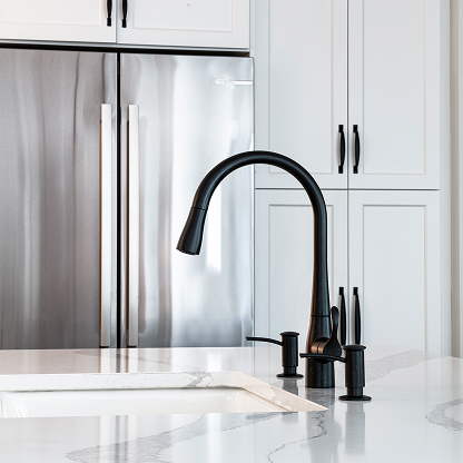 Matte black pull-down kitchen faucet with white quartz countertop and stainless steel appliances