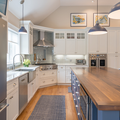 Modern farmhouse kitchen with blue island, hardwood floors, and industrial pendant lights