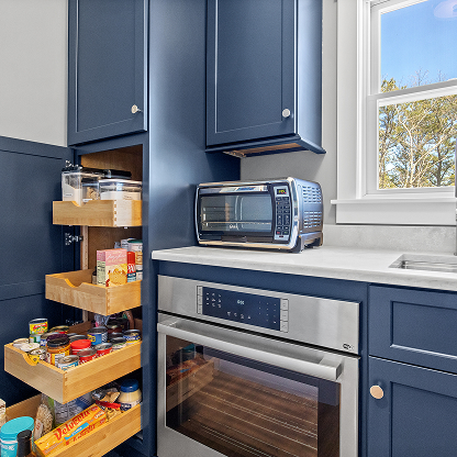 Navy blue kitchen cabinets with pull-out organizers and stainless steel appliances