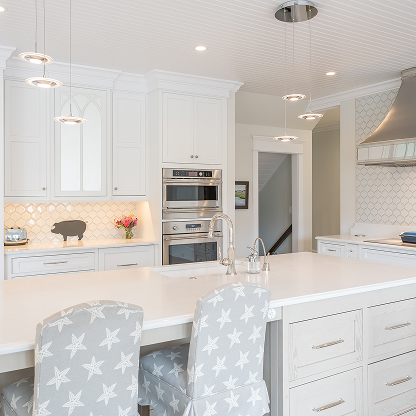 Coastal kitchen with star-print bar stools, white cabinets, and pendant lighting