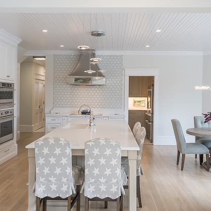White kitchen with fish scale tile backsplash, star-print chairs, and hardwood floors