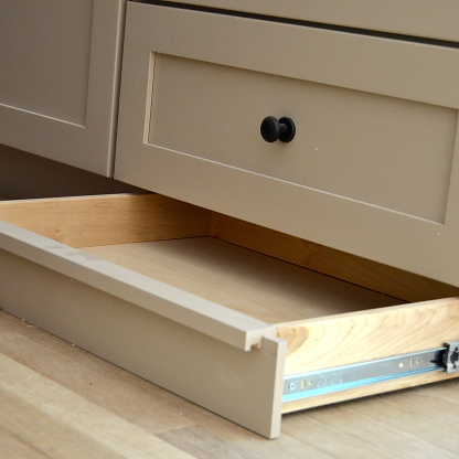 Kitchen toe kick drawer with soft-close hardware and beige painted finish