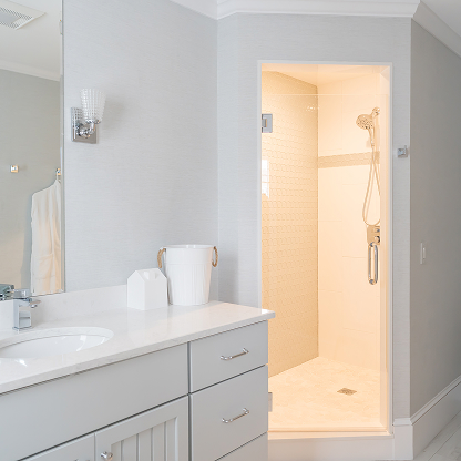 Modern gray bathroom vanity with walk-in shower and chrome fixtures