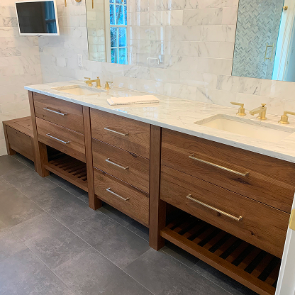 Custom walnut bathroom vanity with marble countertop and brass hardware