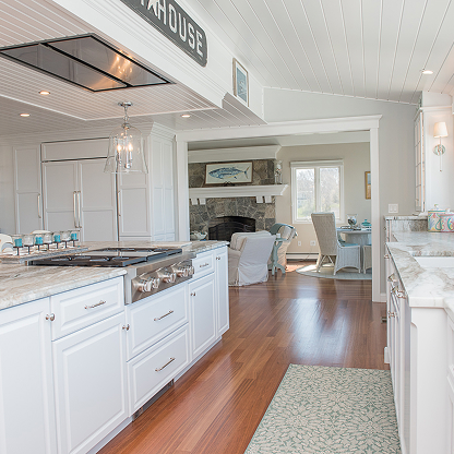 Coastal white kitchen with hardwood floors and open concept to living room