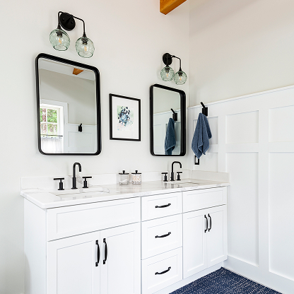 Modern farmhouse bathroom with double vanity, black mirrors, and glass sconces